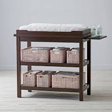 Changing table with basket bins stored on open shelving underneath
