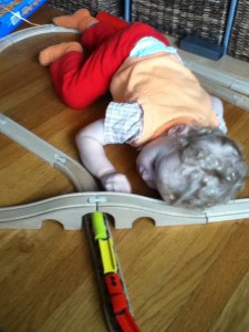 Toddler laying down to play with IKEA wooden train set
