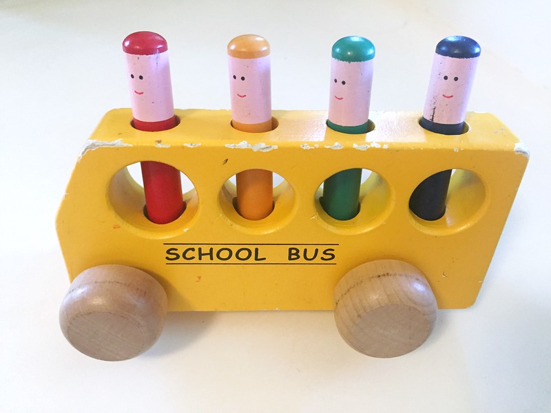 Wooden yellow school bus with painted stick people that pop up