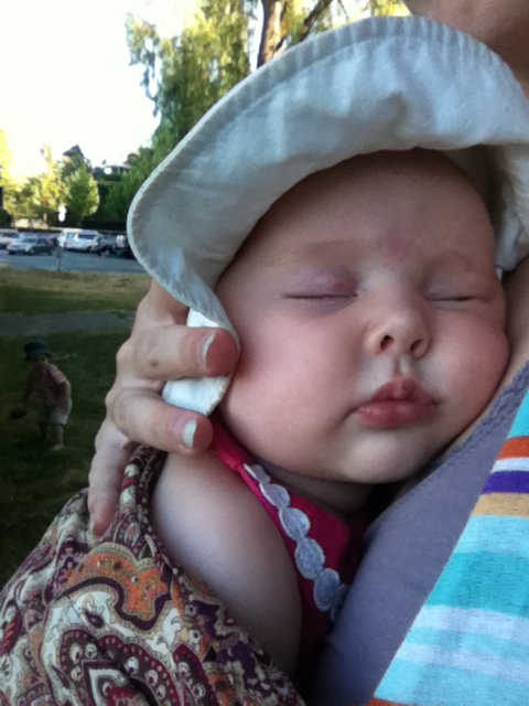 Infant sleeping in sun hat carried in ring sling