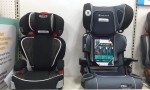 Two belt positioning booster seats side by side on a shelf by Graco and Babytrend
