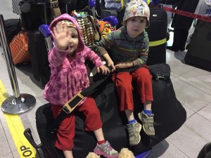 Toddler and preschooler sitting on pile of luggage at airport