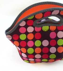 BYO by Built neoprene lunch bag in green orange pink and red polka dot pattern on brown background lined with orange interior