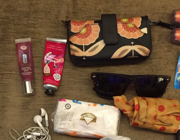 lip gloss, hand cream, wallet, sunglases, tissues laid out together