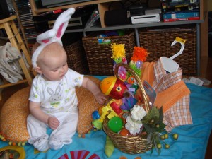 Infant wearing bunny ears exploring contents of easter basket