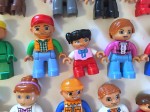 Duplo people lined up in rows with different sizes genders and skin tones