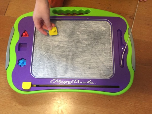 Child's hand with gray magna doodle board
