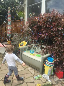 Preschooler popping bubbles from automatic bubble blower machine