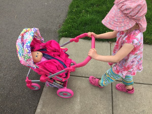 Child pushing Lissi stroller on sidewalk