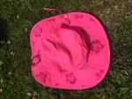 Sun Protection Zone bright pink wide brim sun hat with chin strap and purple flower designs that appear in sunshine