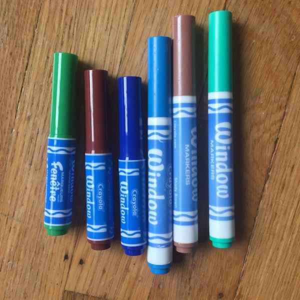 Mini and regular window markers from Crayola shown side by side on wooden floor