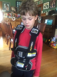 Child wearing ride safer harness inside house