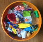Large orange bowl filled with small plastic toys, stickers, sunglasses, balloons, and more for trick or treating