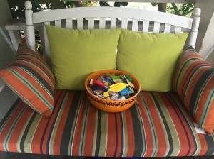 Orange Halloween bowl sitting on white front porch swing striped cushions