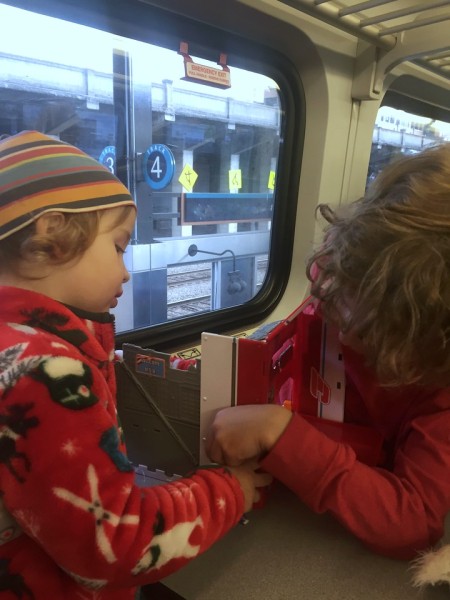 Preschooler and child playing with Super Wings New York playset on board train
