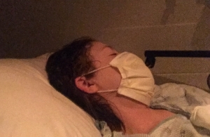 Woman in hospital bed with mask covering lower face