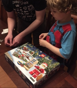 Adult helping child assemble Legos from City advent calendar