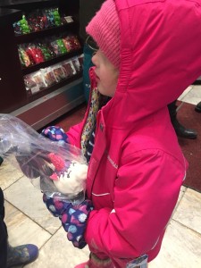 Child wearing Columbia Frosty Slopes jacket and snow bib while holding unicorn candided apple