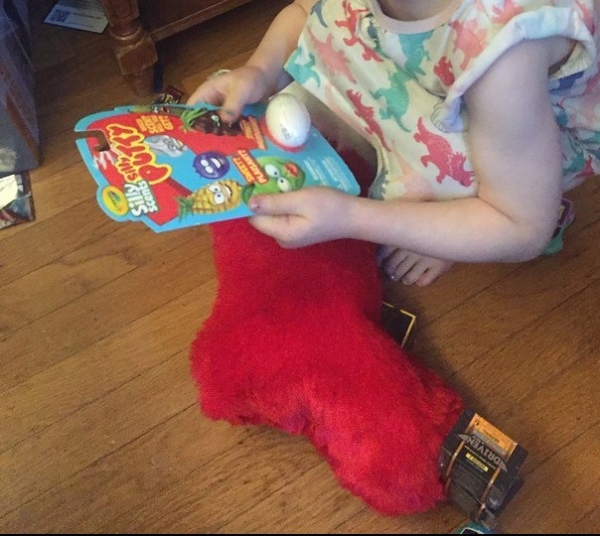 Child holding scented Silly Putty package pulled from red fuzzy Christmas stocking