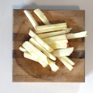 Pile of apple fries sliced rectangular sticks on cutting board