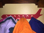 Kids coats hanging on airplane metal red coat hooks mounted on wall