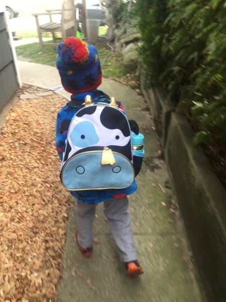 Child walking down sidewalk wearing Skip Hop cow design little kids toddler backpack with skip hop water bottle in side mesh pocket