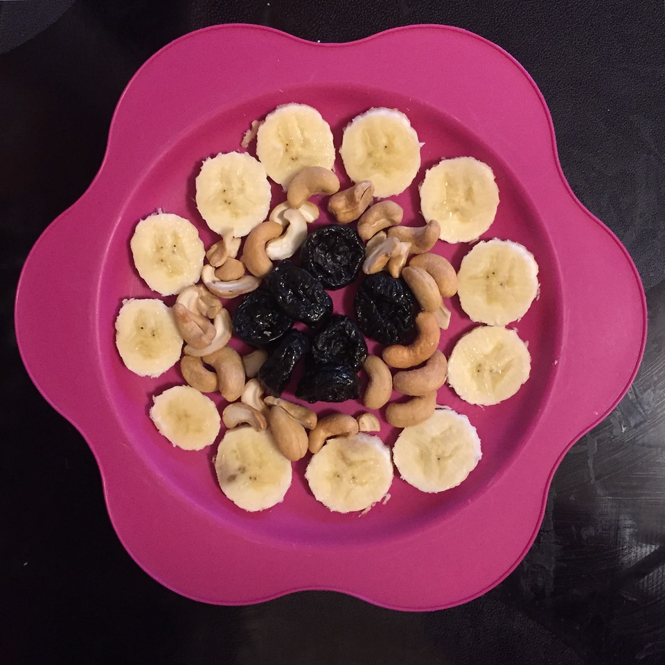 Kid snacks healthy fruit dried fruit nuts arranged on bright pink flower plate