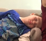 Child sleeping sideways on sofa next to adult passed out kid
