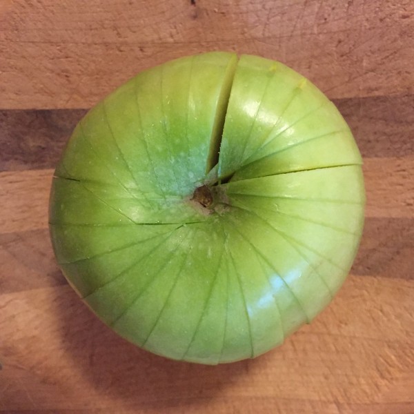 Green apple on cutting board cut into slices