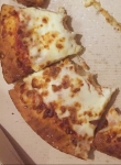 Half eaten cheese pizza in cardboard take out box