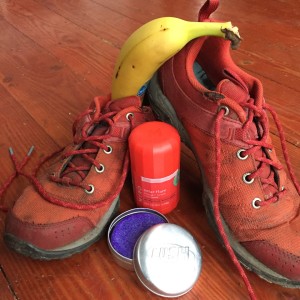 Tennis shoes sneakers running shoes Columbia with banana, LUSH solid shampoo in open tin, and Myro Solar Flare deodorant