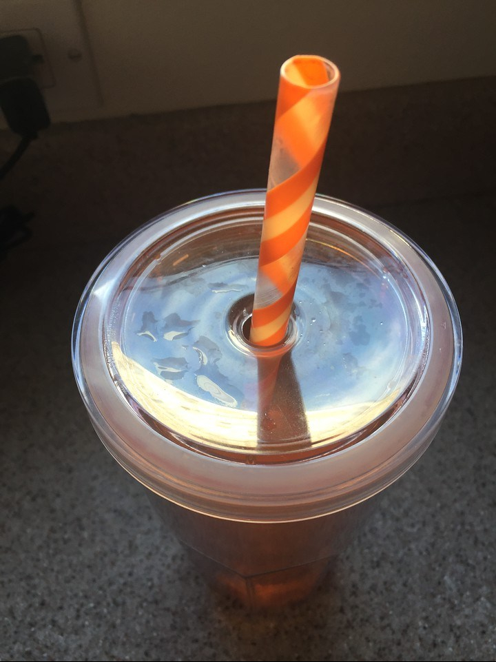 Orange striped reusable straw in clear cup lid