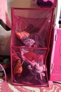 Pink collapsible laundry bin half filled with child's dirty clothes