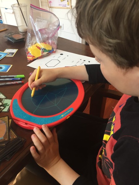 Nine year old boy drawing on boogie board at table