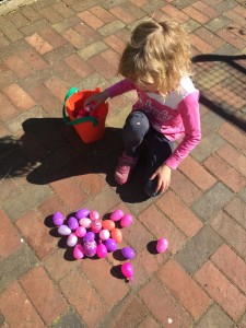 Girl with pink and purple plastic Easter eggs sorted by color to hunt