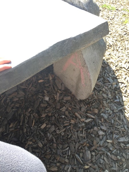 Letter A drawn in pink sidewalk chalk on leg of bench