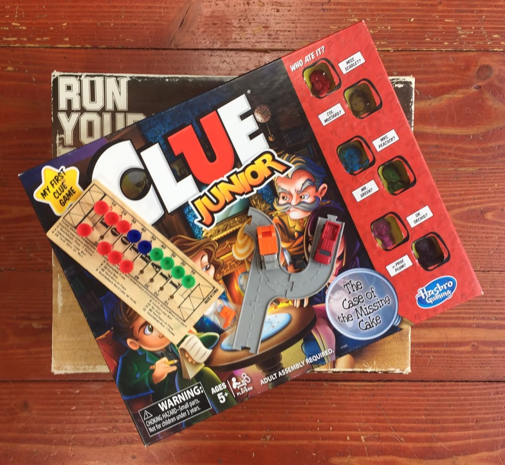 Run Yourself Ragged game in box, Clue Junior game in box, football peg game, and Driven tiny trucks in stack