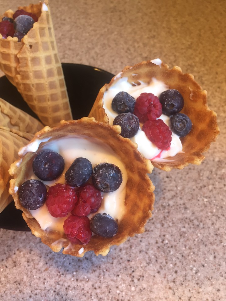 Yogurt cone treats ice cream waffle cone filled with vanilla yogurt, raspberries, and blueberries