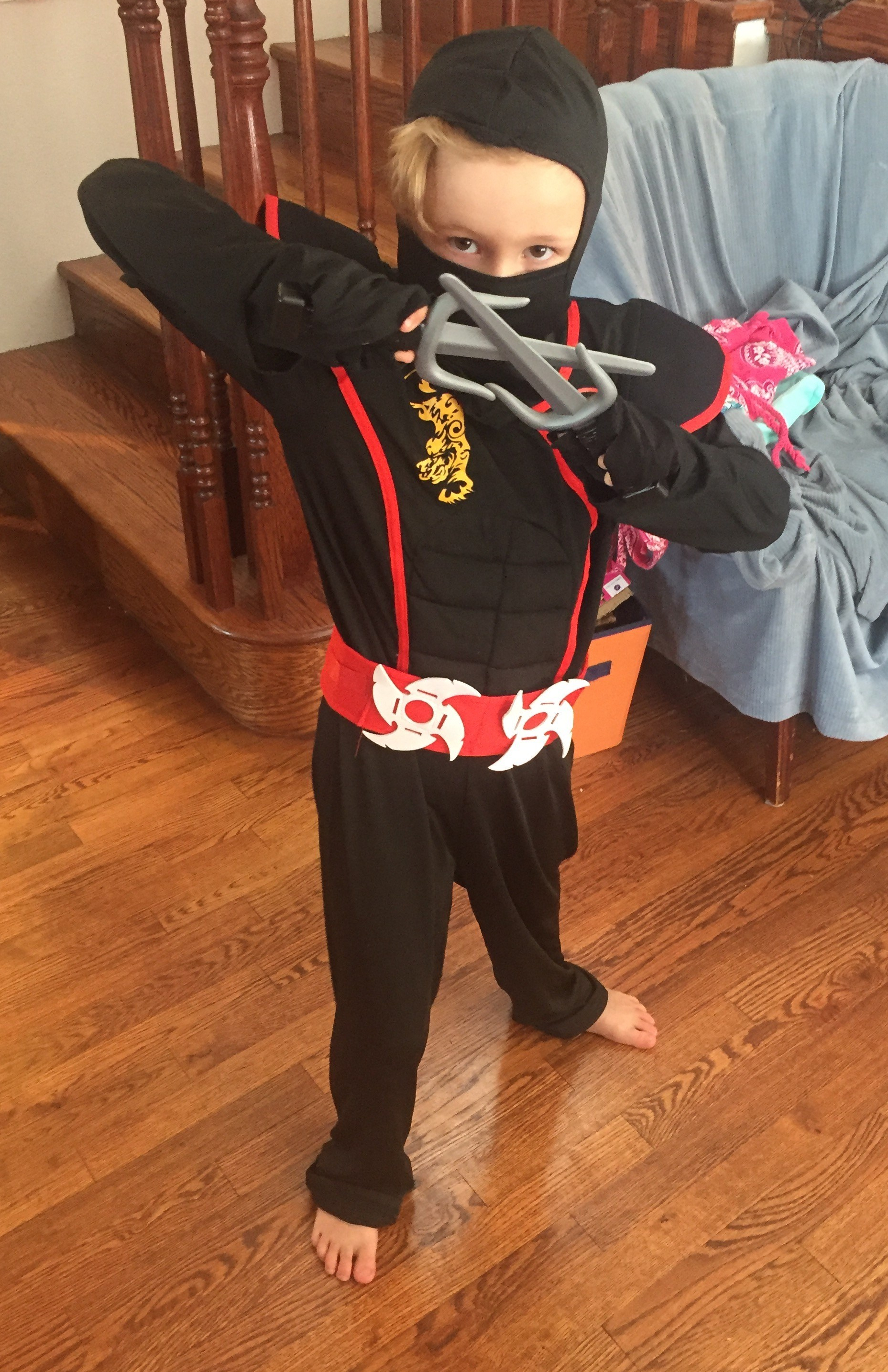 Eight year old girl dressed up in ninja costume with black face mask