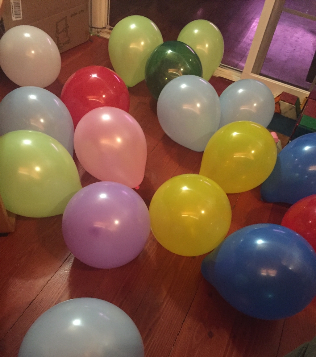Birthday balloons inflated and scattered over hardwood floor