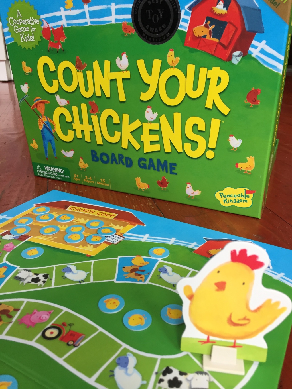 Count Your Chickens mother hen on board in front of box cooperative board game for young kids by Peaceable Kingdom