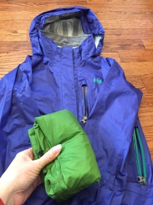 REI Rainwall jacket in blue with green one folded up