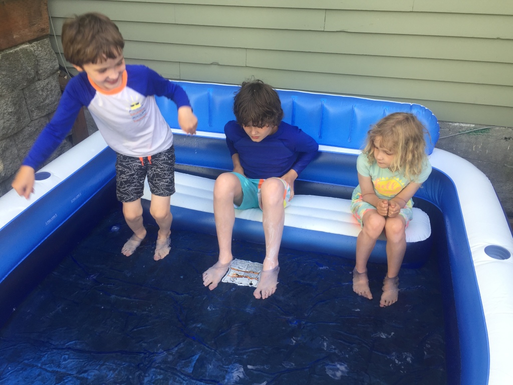 Kids sitting in inflatable splash pool with bench and cup holders from Sun Squad