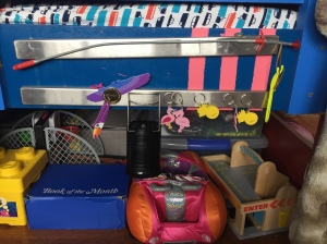 Two magnetic knife rack wall strips attached to side of child's bed frame holding key chains, lantern, pretend coin, and more