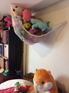 Stuffed animal hammock hung from slanted ceiling filled with stuffed animals above child's bed