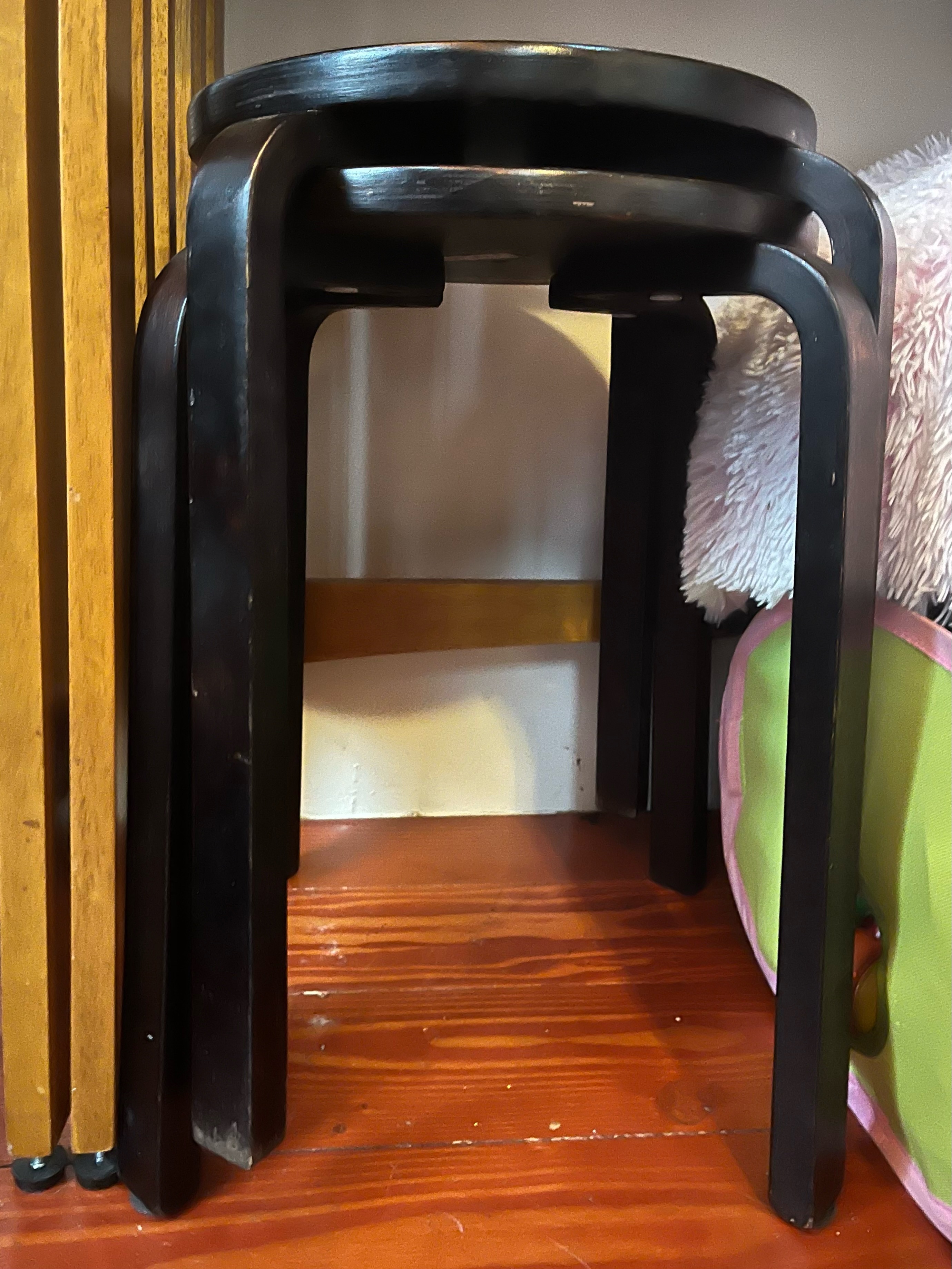 Dark wooden stacking stools stored underneath table