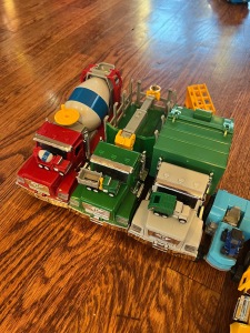 Driven Micro Series vehicles toys with Pocket Series matching tiny vehicle toys on top of cement mixer, log lifter, truck, and garbage truck