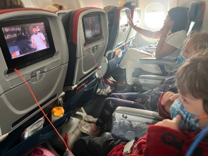 Kids on board airplane with JetKids BedBox tucked underneath seat