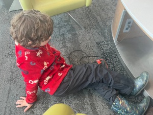 Seven year old child sitting on floor of airport listening to MP3 player