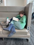 Child reading Rick Riordan book in airport lounge before flight